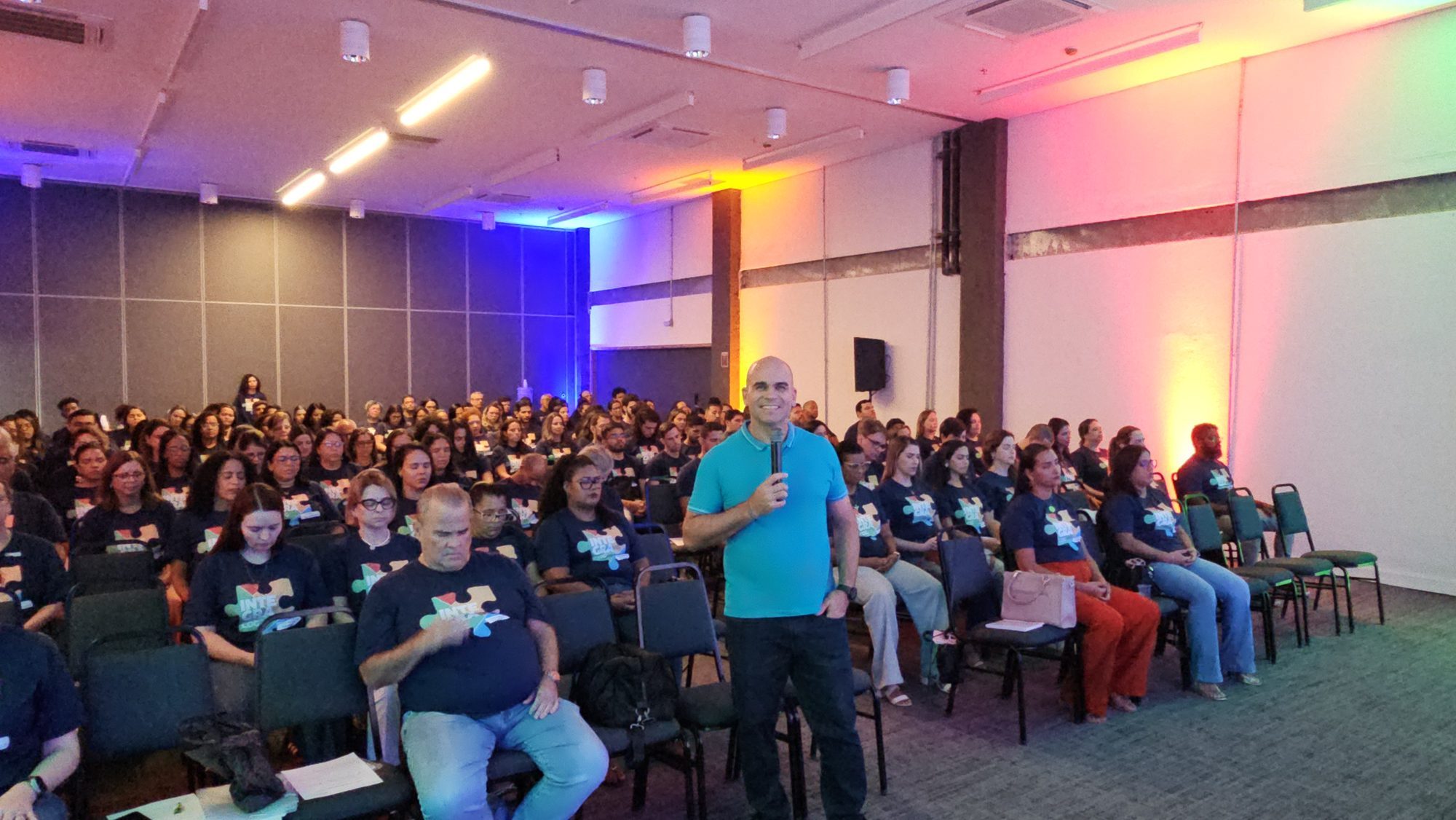 Felipe Lapa de pé no meio de um auditório cheio, com 180 educadores do Colégio Cognitivo